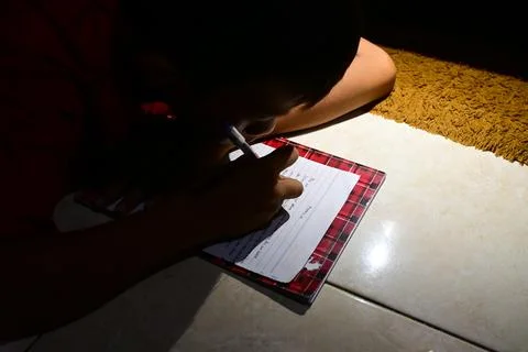 A child is learning to write in dim light, selected focus Stock Photos