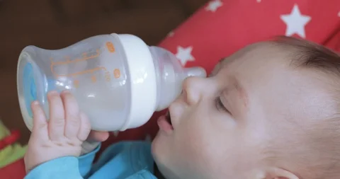 Child learns to drink from a bottle Vídeos de archivo 105646846