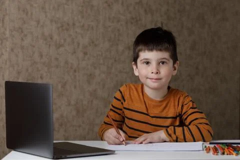 The child learns remotely through the computer. The boy draws with pencils and Foto stock