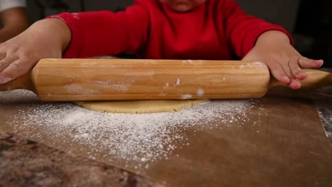 The child learns to roll the dough with a rolling pin Stock Footage 143524918