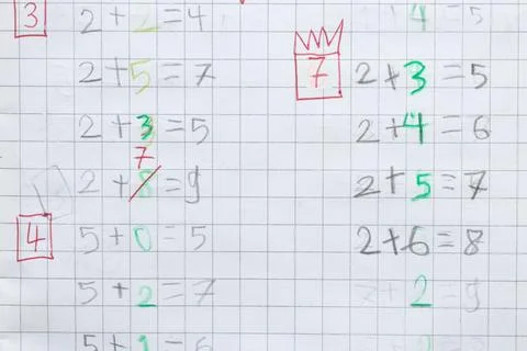 A child learns to solve simple math problems in a gridded notebook. Teachin.. Stock-Fotos