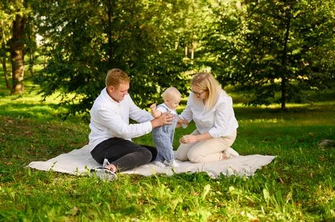 Child learns to take first steps, learns to walk. Toddler, supported by father Stock Photos