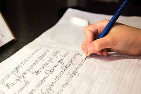 The child learns to write letters and words with a pencil in a notebook Stock Photos