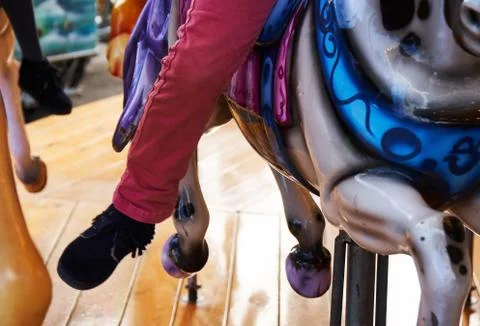 Child legs hanging from carrousell horse Stock Photos