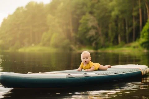 The child lies floating on the water on a large sup board. Water sports Stock Photos