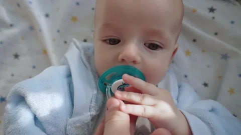 The child lies on his back, plays with the pacifier. Vídeo Stock 194379846