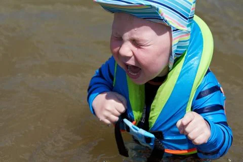 Child in a life jacket crying while standing in the water Stock Photos