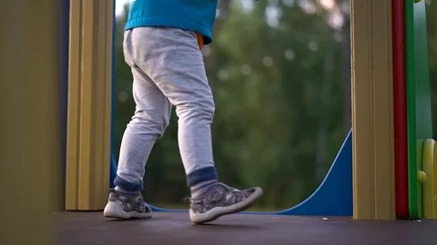 A child/ little boy in a blue jacket and grey pants is playing on the Playground Stock Footage 112080101