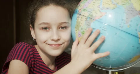 Child looking at camera smiling holding globe next to him, technology for Stock Footage 248820878
