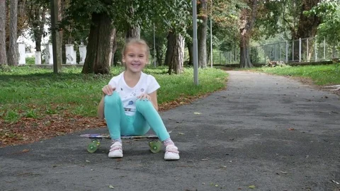Child looking into the camera while sitting on the skateboard. Video stock 80007855