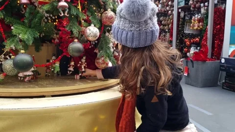 Child looking with curiosity and touching a beautiful decorated Christmas tree Stock Footage 257418595