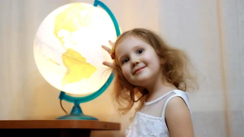 Child looking on the globe and world. Baby girl looks at the map and showing the Stock Footage 104587715