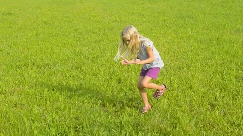 The child is looking for insects in the grass in the summer. Stock Footage 79798556