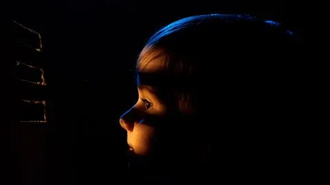 Child looking up at light shining through window blinds Stock Photos