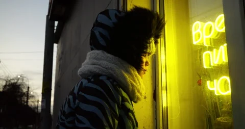 Child Looking at Neon Light Reflection Outdoors in Urban Winter Setting Stock Footage 297704413