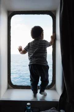 Child looking out ship window at sea 스톡 사진