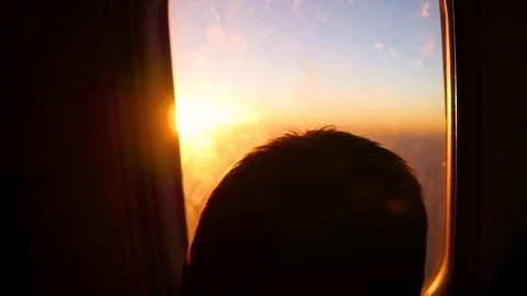 A child looking out the window of an airplane at sunset Video stock 74505992