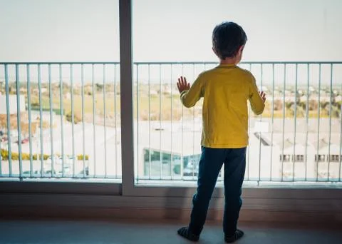 Child looking outside through the window with hope Foto stock
