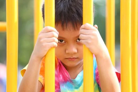 Child Looking Through Playground Bars in Bright Colors Stock Photos