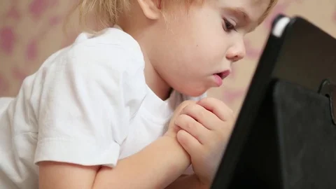 Child looks cartoons on tablet pc closeup 動画素材 70596207
