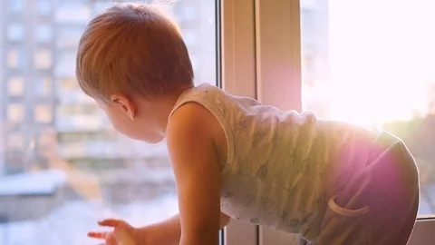 A child looks out the window through the sun in slowmotion Video stock 73546812