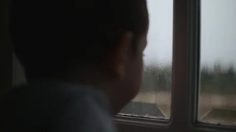 Child looks at the rain behind the window. Stock Footage. Stock Footage