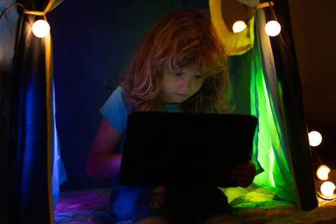 Child lying in bed and learning in virtual online school class. Kid working on Stock-Fotos