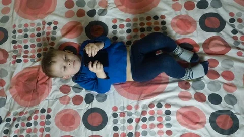 Child lying on the bed and looking at an electronic smartphone display Video stock 113059371