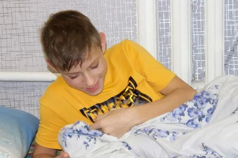 The child is lying on the bed and playing games on a smartphone . Stock Photos