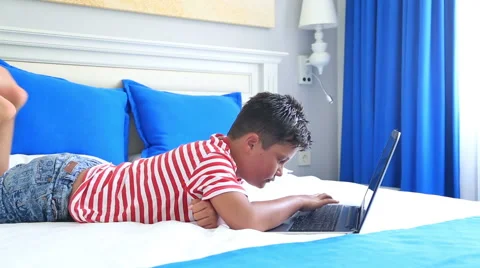 Child lying on a bed and using laptop computer 5 Stock Footage 64821995