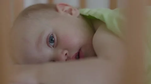 Child lying in crib face in close-up. Comfort of cozy crib boy drifts into realm Stock Footage 279515024