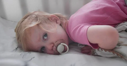 Child lying in crib with soft bedding after waking up Stock Footage 337971038
