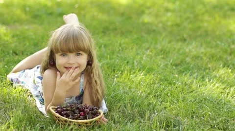 Child lying on the grass with a sweet cherry Stock Footage 11214050