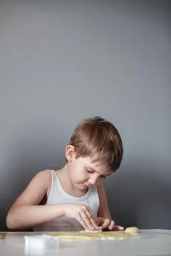 The child makes cookie molds on a white table. Preparation of homemade desser Stock Photos