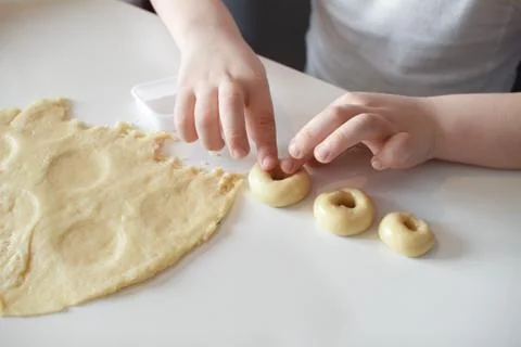 The child makes cookie molds on a white table. Preparation of homemade desser Foto stock