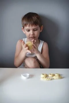The child makes cookie molds on a white table. Preparation of homemade desser Stock Photos