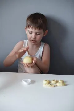 The child makes cookie molds on a white table. Preparation of homemade desser Stock Photos