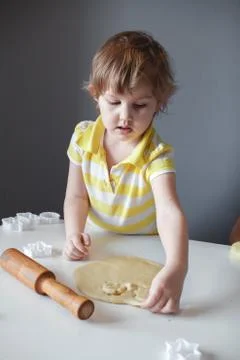 The child makes cookie molds on a white table. Preparation of homemade desser Stock Photos