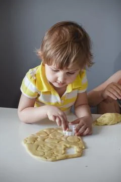 The child makes cookie molds on a white table. Preparation of homemade desser Stock Photos