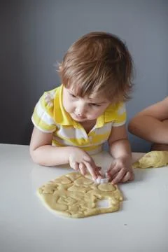 The child makes cookie molds on a white table. Preparation of homemade desser Stock Photos