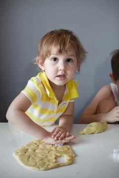 The child makes cookie molds on a white table. Preparation of homemade desser Stock Photos