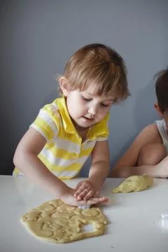 The child makes cookie molds on a white table. Preparation of homemade desser Foto stock