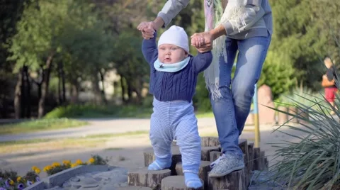 The child makes the first steps, mother help him. Autumn park Stock Footage 68810925