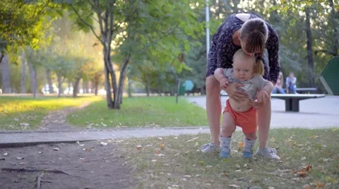 The child makes the first steps, mother help him. Autumn park Stock Footage 68811194