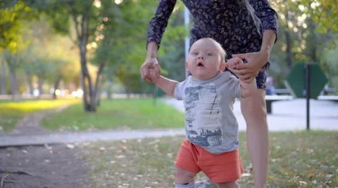 The child makes the first steps, mother help him. Autumn park Stock Footage 68811360