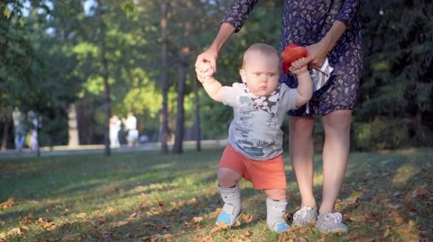 The child makes the first steps, mother help him. Autumn park Video stock 68811791