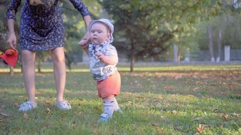 The child makes the first steps, mother help him. Autumn park Stock Footage 68811959