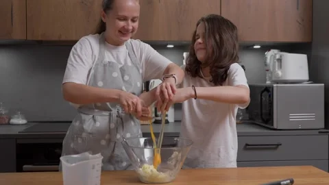 Child makes a funny face of disgust feeling a slimy egg while baking. Video stock 311806979