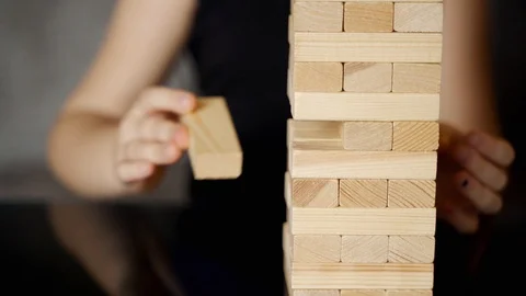 Child makes her move in Jenga tower. Slow motion Stock Footage 128423006