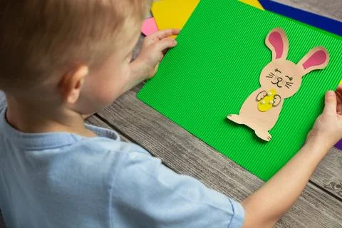 A child makes a postcard with an Easter bunny with his own hands. Application Stock Photos